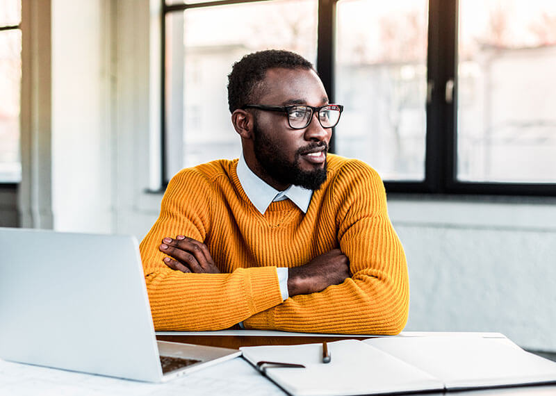 A man in a yellow jacket looking out the window of an office