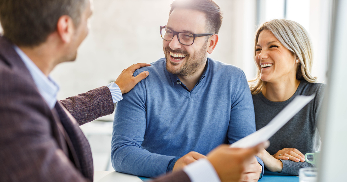 Happy couple talking to their lender about their home loan in the office