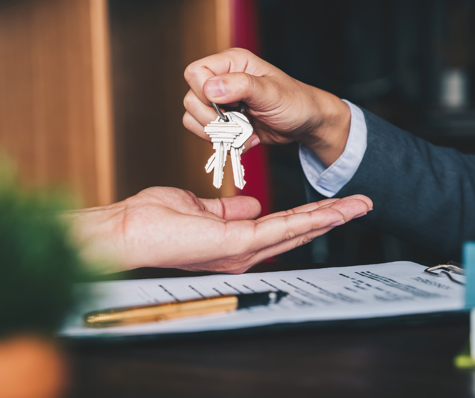 Closeup of real estate agent handing house keys to a new homeowner