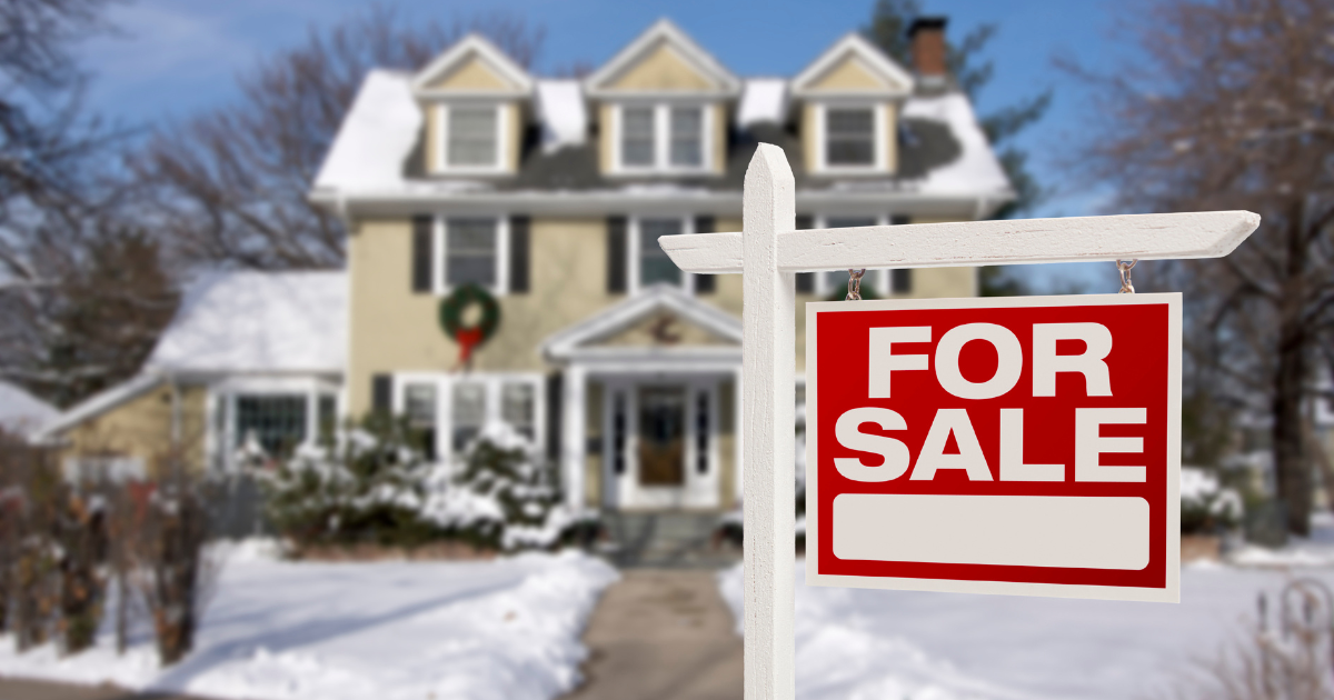 Home For Sale Real Estate Sign in Front of Beautiful New House in the Snow