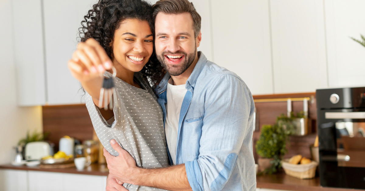 Young married couple showing keys to new house