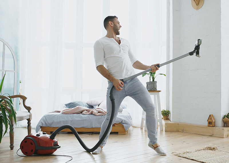 A man holding a vacuum while pretending to use it as a guitar