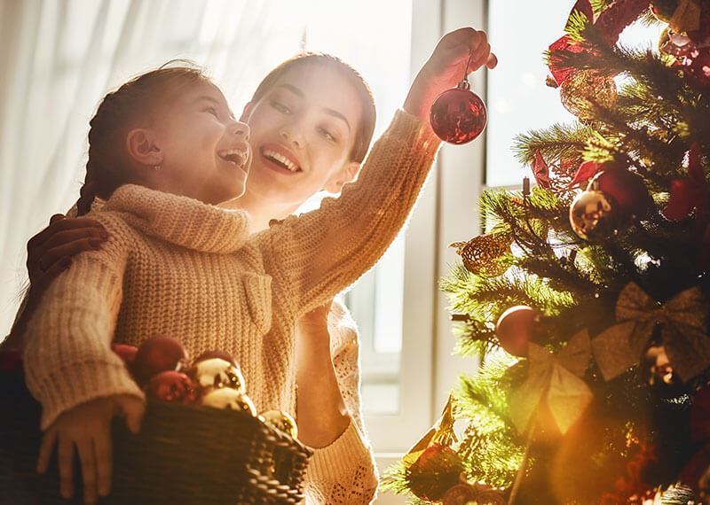 A Mother and daughter putting ornaments on a Christmas tree