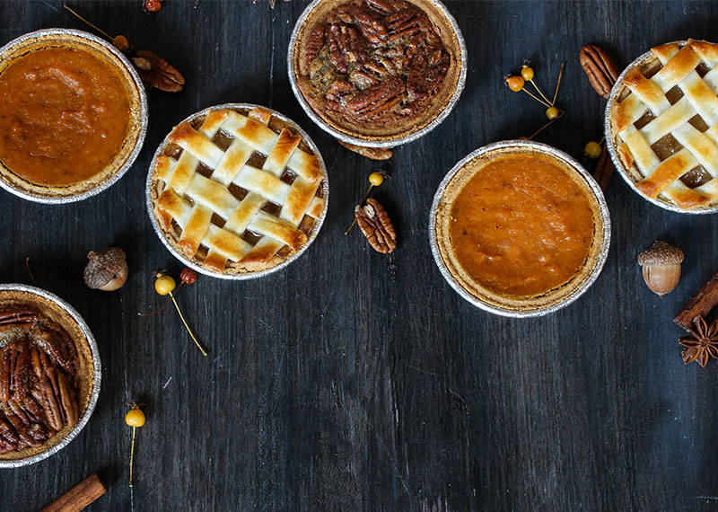 Six pies sitting on a black wooden table