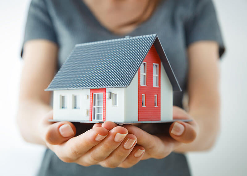 A woman holding a red and white house in her hands