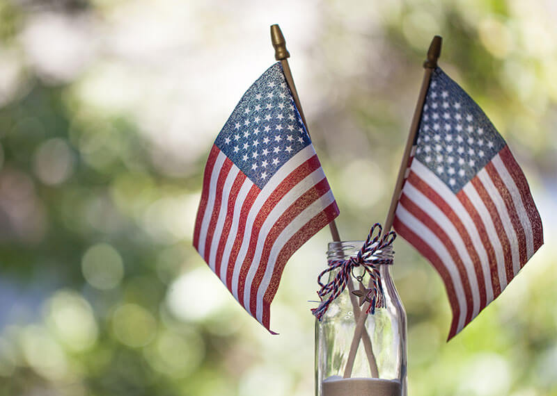Two American Flags sitting in a mason jar outside