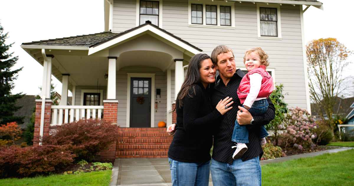 family standing in front of suburban home on a fall day