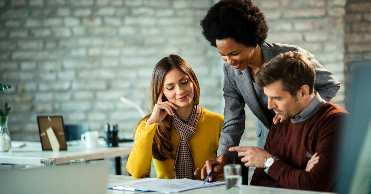 Happy loan originator and her clients listening while analyzing a document during a meeting