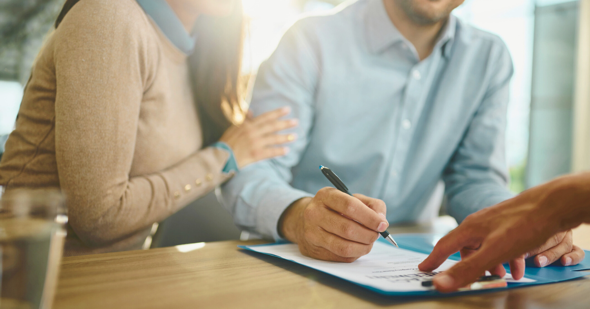 Close up of unrecognizable couple signing a contract in the office