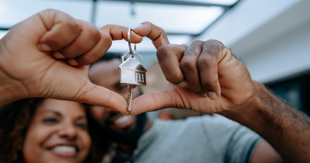 Couple hold house key to new home with hands in heart shape