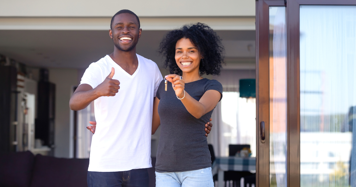 Couple standing on terrace holding keys to their new house