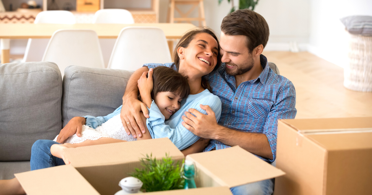 Family with kid embracing on a sofa while moving into new home