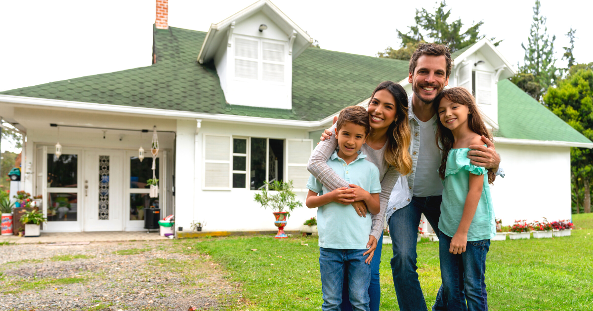 Happy family standing outside their new house and looking at the camera smiling