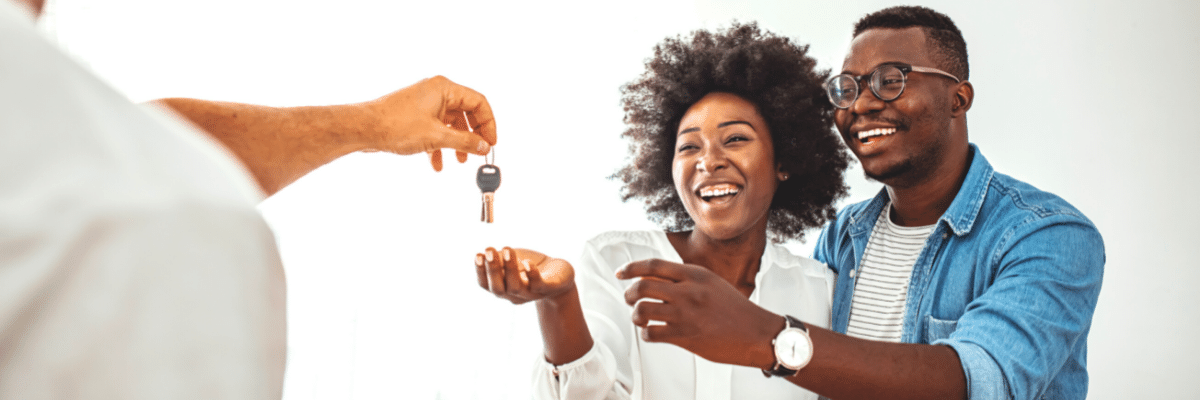 A young couple receive the keys to their new home from a real estate agent