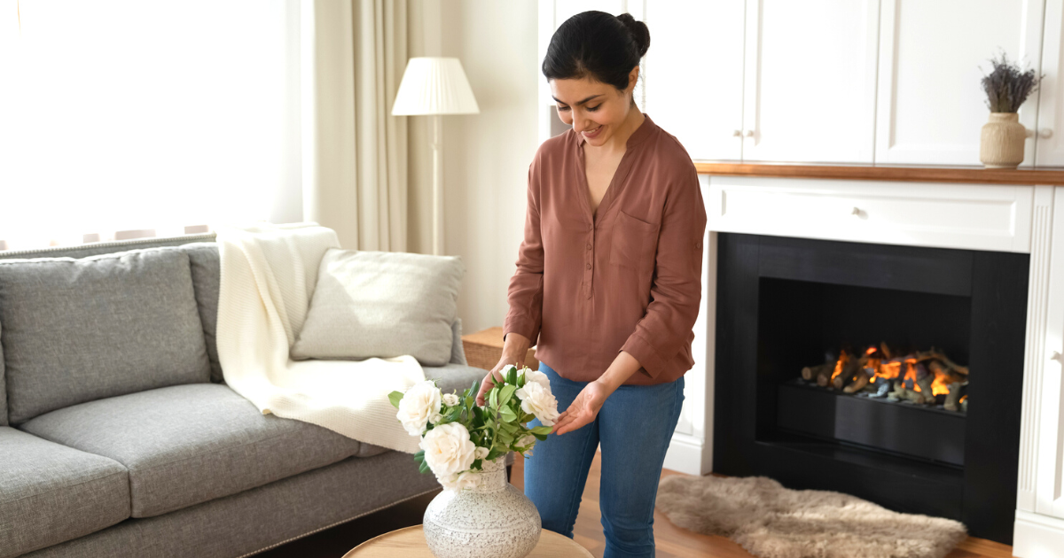 Happy millennial woman decorating luxury living room with flowers
