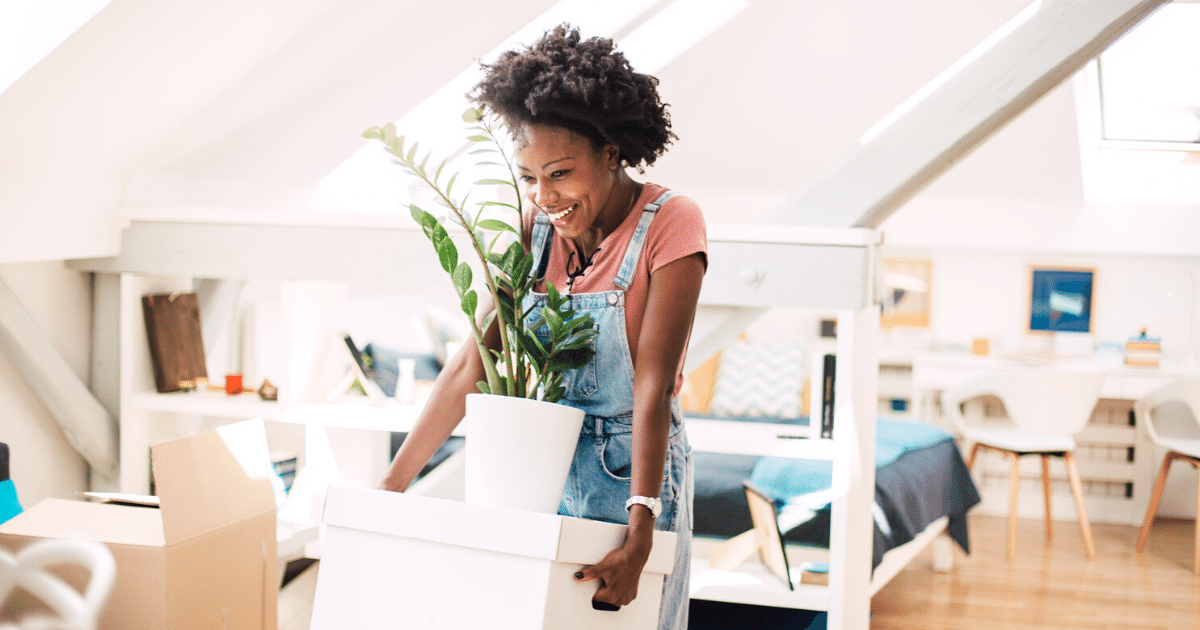 Young woman carrying her belongings while moving into the new home.