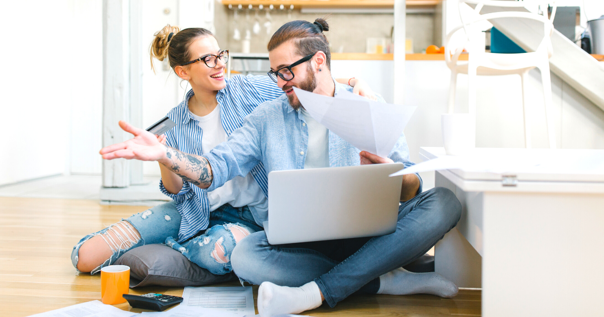 Happy young couple using a credit card and going through home finances