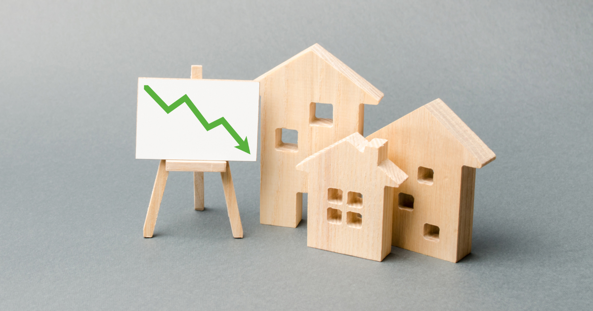 Wooden houses and an easel arrow down. The fall of the real estate market. concept of value or cost decrease. low liquidity and attractiveness. cheap rent. Reduced demand and market stagnation