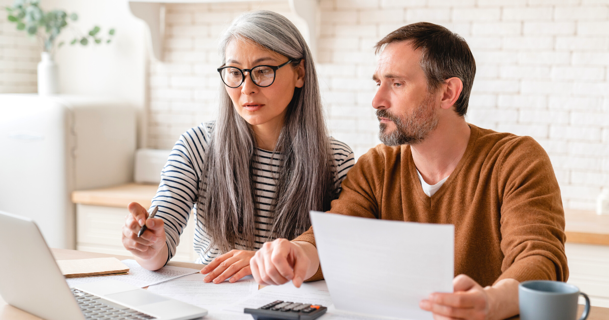 Middle-aged wife and husband counting funds with laptop