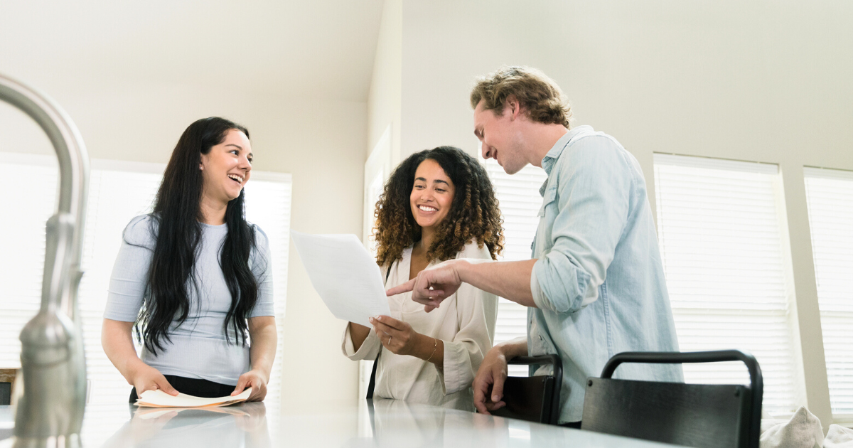 Real estate agent and couple smile while discussing contract