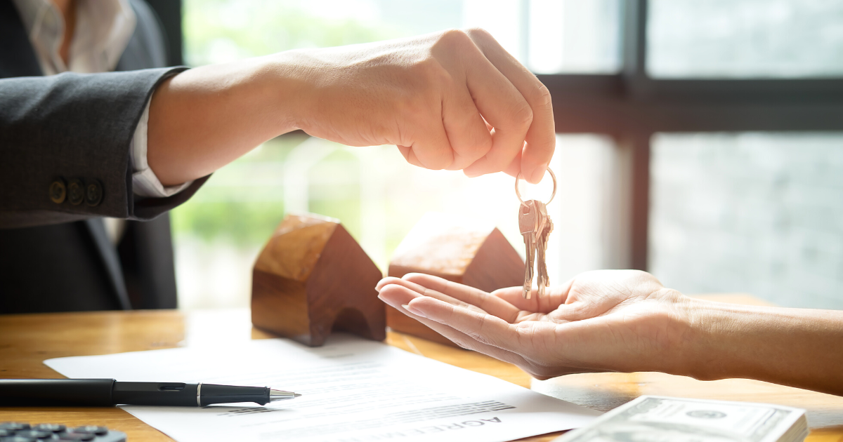 Estate agent giving house keys to customer and sign agreement in office