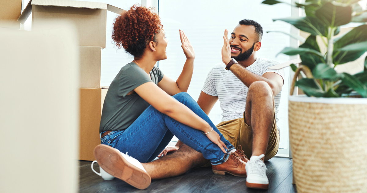 Shot of a young couple giving each other a high five while moving house