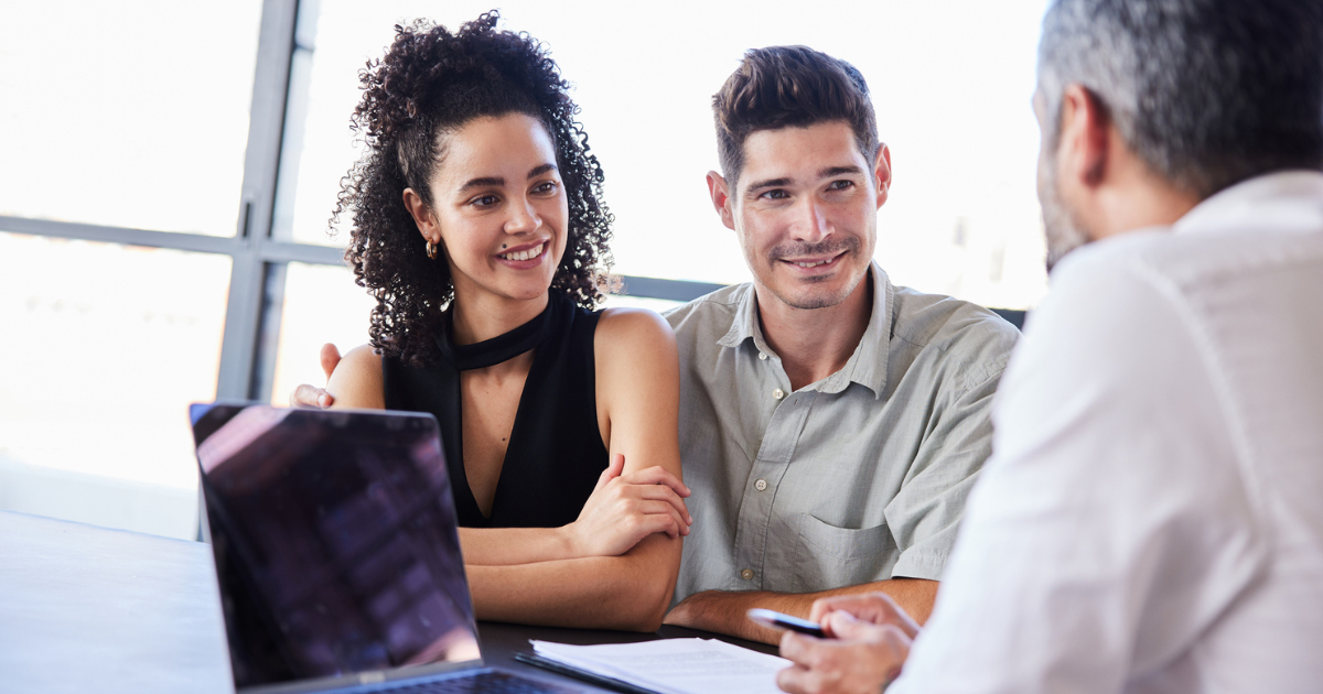 Smiling young couple discussing paperwork with their financial advisor in his office