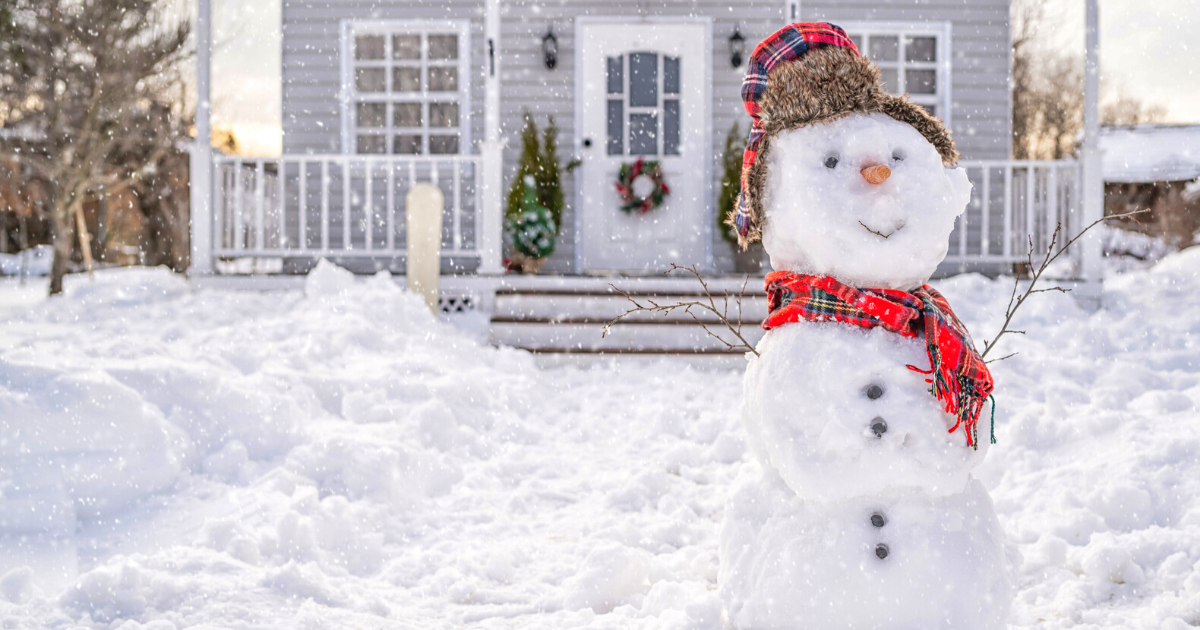 Smiling snowman in front of the house on winter day