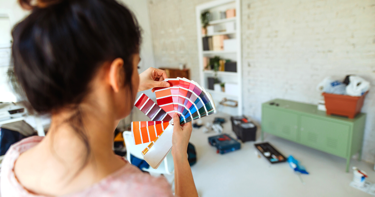 Young woman during reconstruction of home, holding color chart and choosing the right color for the wall
