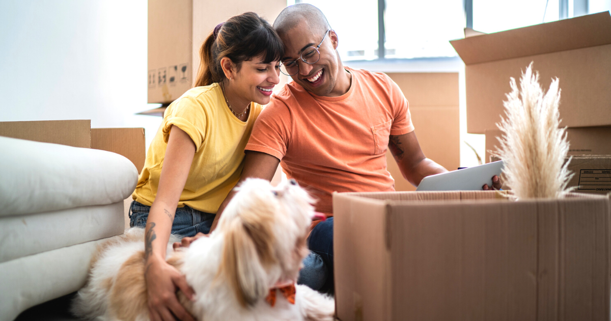 Young couple with their dog packing and moving boxes at home