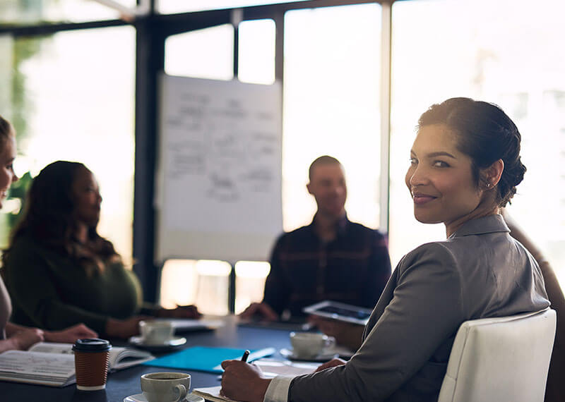 Female looking at camera in the office with two coworkers Female looking at camera in the office with two coworkers