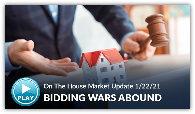 An auctioner holding a gavel next to a small white house