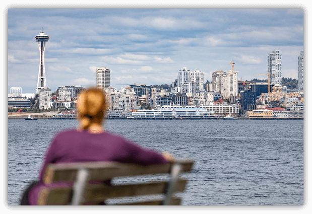 Woman on a bench looking at Seattle skyline