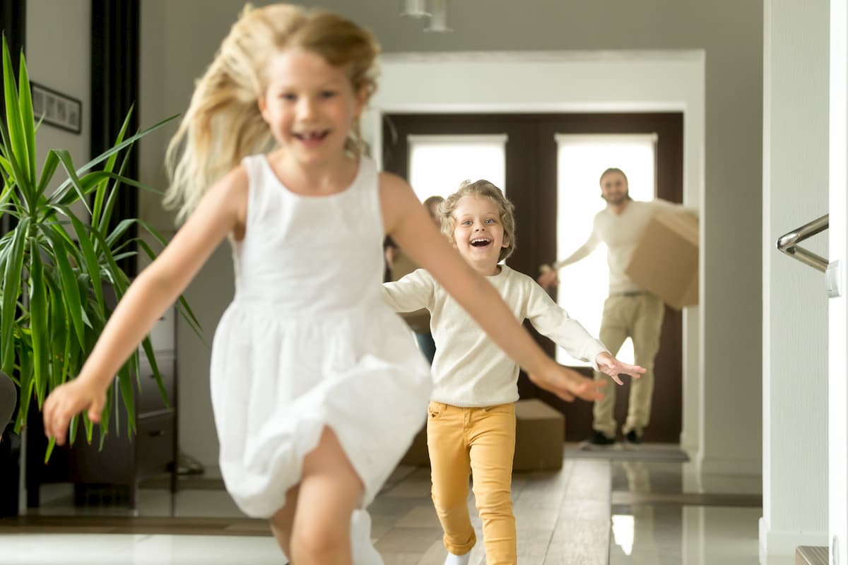 An adult holding the hands of a child who is holding a blue paper house