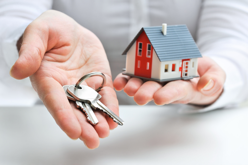 Man holding small home and keys in hands